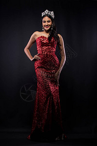 亚洲女子红色晚礼服带钻石皇冠腰带的选美小姐选美大赛全长背景图片