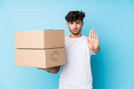 年轻的阿拉伯男子拿着孤立的盒子站着伸展的手显示停图片