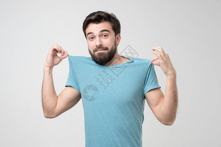 帅气自信的西班牙裔男人一边吹嘘自己的新蓝色T恤图片