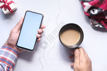 手持智能手机和桌上咖啡图片