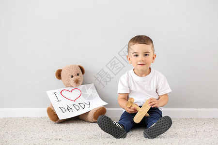 让小可爱男孩带着玩具和贺卡迎接父亲节的爸图片