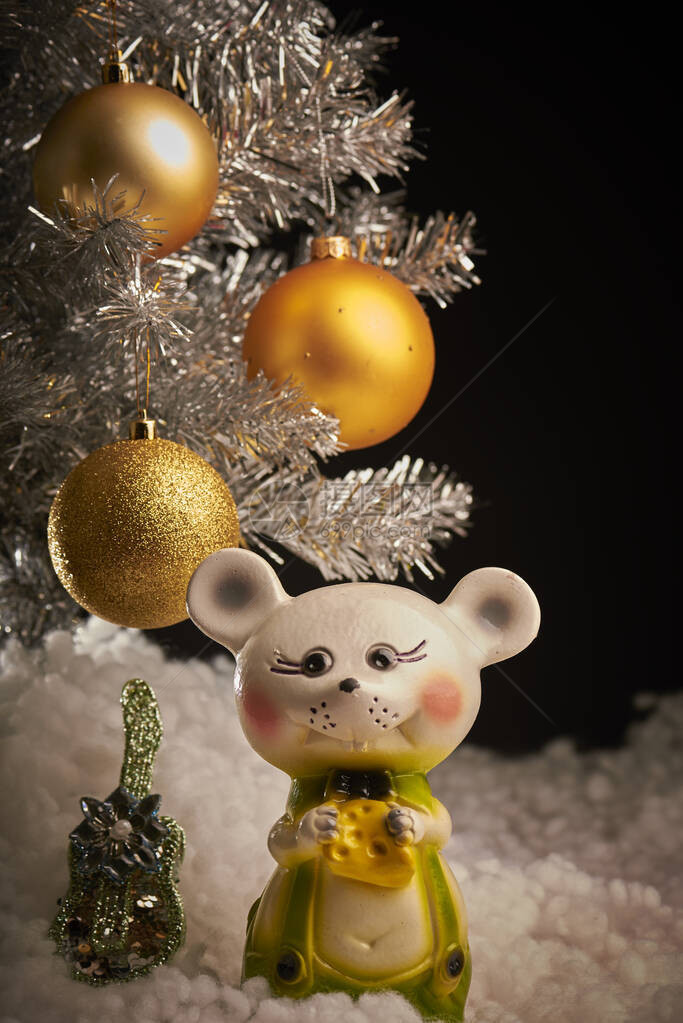 新年假期在带有黄色球的黑色背景银色圣诞树上树下是一把玩具吉他图片