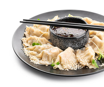 白色背景上带有美味日本饺子和酱汁的盘子背景图片