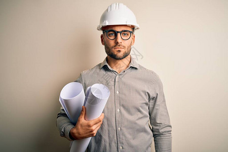 戴承包商头盔的年轻建筑师在孤立的背景下拿着项目纸计划图片