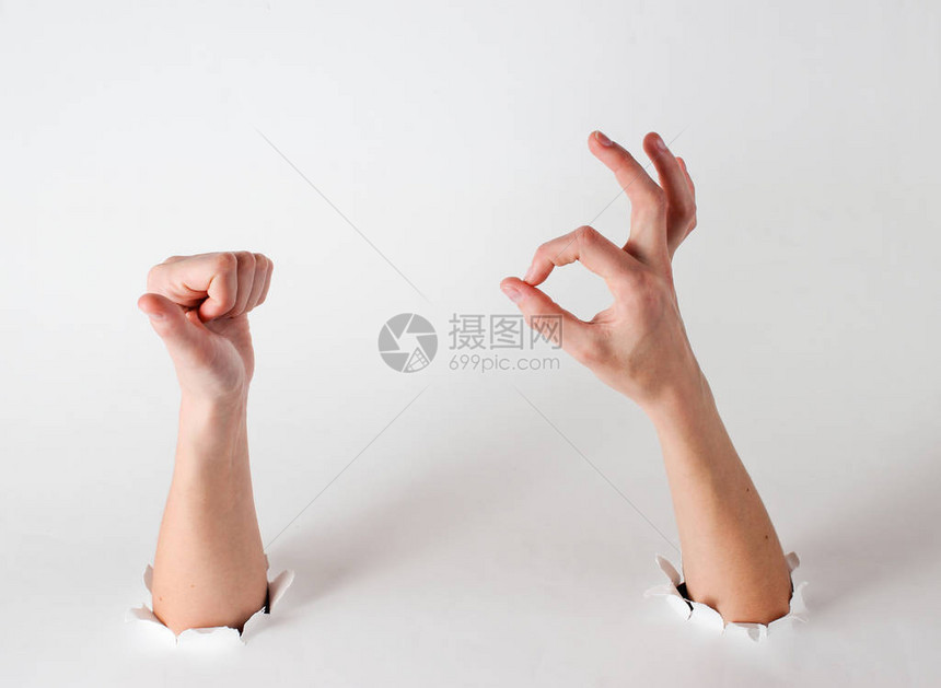 女手举起拇指通过白色背景的撕破洞图片