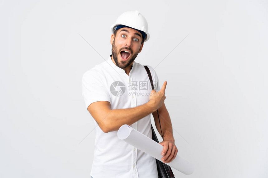年轻建筑师戴头盔持有白色背景孤立的蓝图的青年建筑师男子惊图片