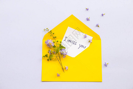 我想念你的留言卡笔迹和紫花安排在黄色信封上背景图片