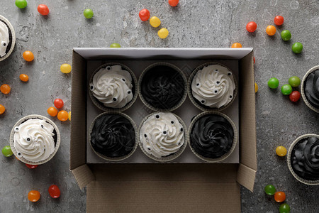 在混凝土灰色面上分散的多彩圆帽旁边的盒子里可以看到美味图片