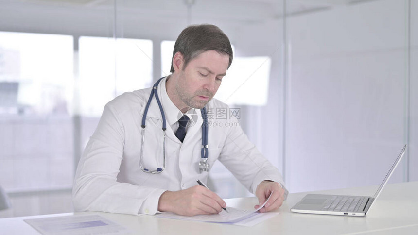 严肃的中年医生在诊所做文书工作图片