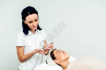 美容师和病人而眼睫延伸程序在白色背景图片