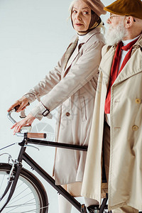 有自行车的时装年长妇女的侧边视线看着穿白色孤立的海沟大图片