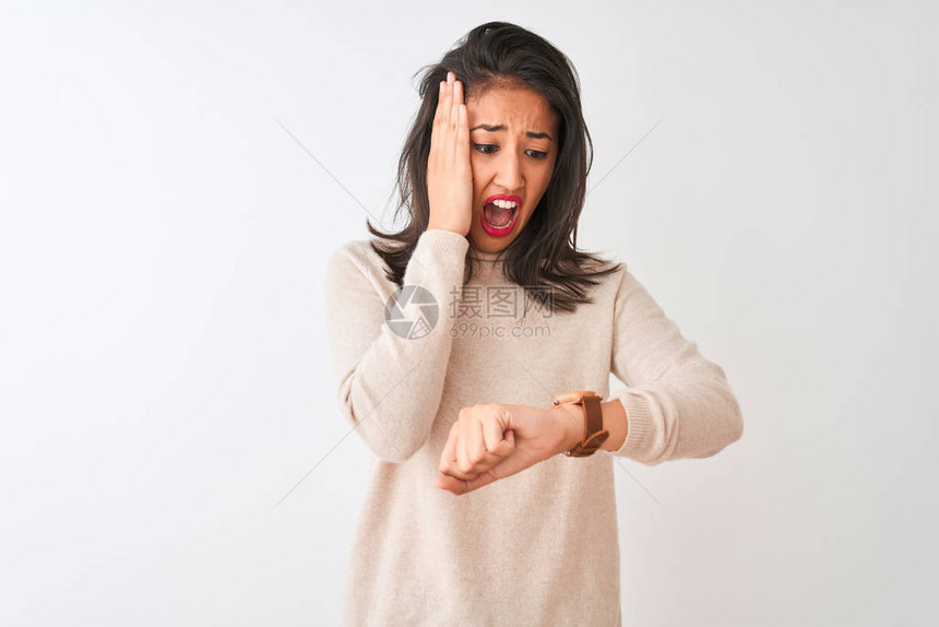 美丽的女人穿着高领毛衣站在孤立的白色背景上看着手表时间担图片