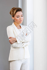穿着白色西装的成功的女商人的肖像靠在墙图片