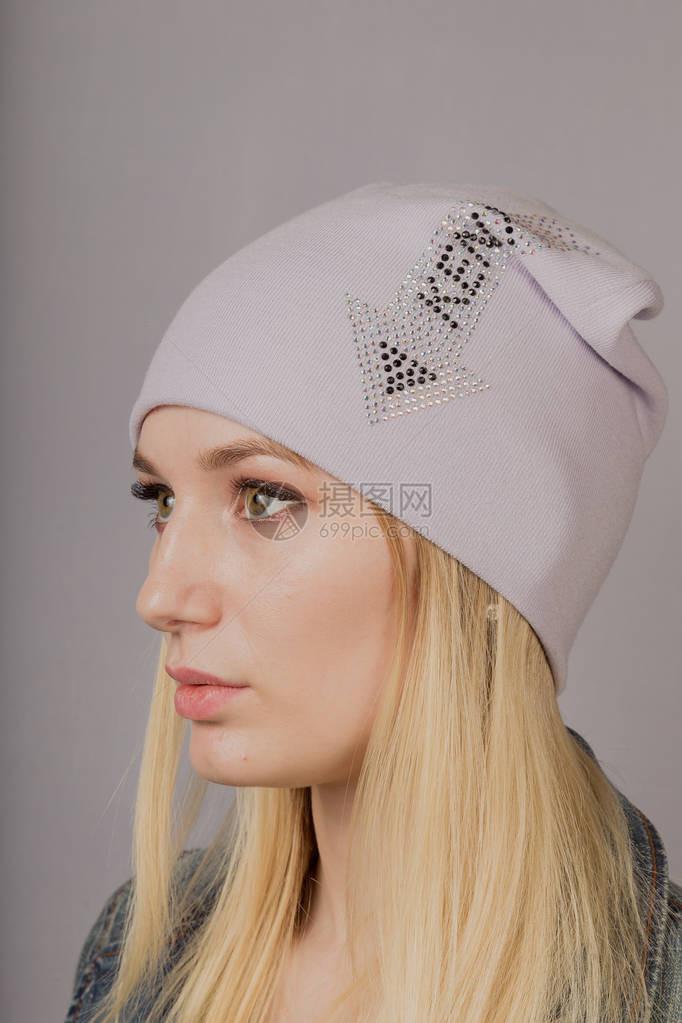 一个美丽的年轻女孩的肖像在一个时髦的帽子上用灰色背景图片