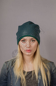 一个美丽的年轻女孩的肖像在一个时髦的帽子上用灰色背景图片