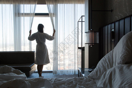 站在卧室窗户旁拉开窗帘的女浴袍图片