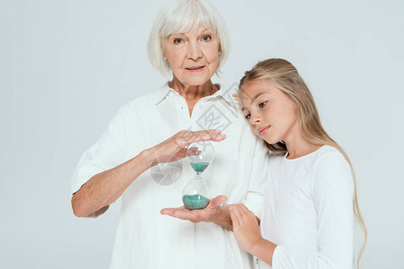 孙女拥抱祖母沙漏被灰色隔离背景图片