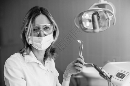 牙科办公室有仪器黑白相片的女牙医生肖像图片
