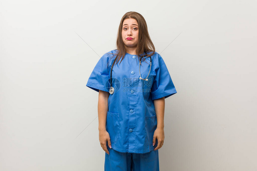 年轻女护士对抗白墙的肩膀和睁开的图片