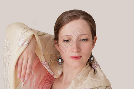 一个美丽的年轻女子跳舞弗拉门戈的特写肖像肩膀上有一条带有刺绣的米色披肩眼睛半睁着一只手举起背景图片