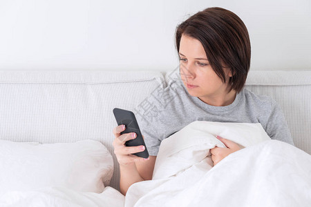 女人坐在床上时用智能手机图片