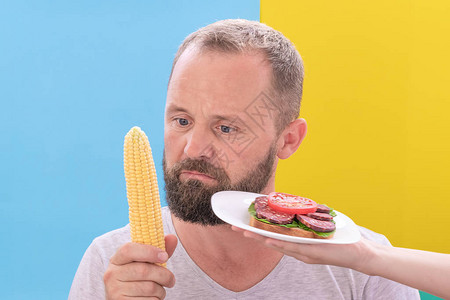 有趣的胡子男人在想玉米和三明治之间该吃什么图片