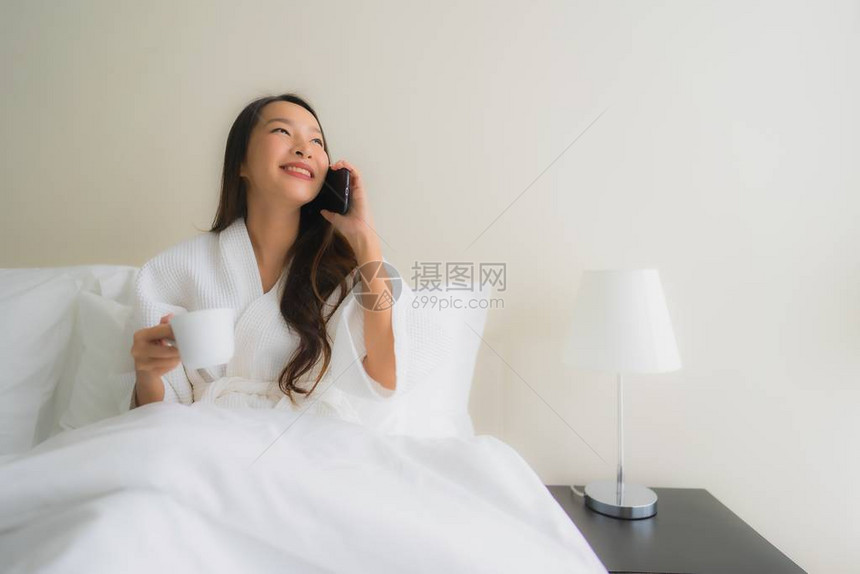 卧室内床上摆着咖啡杯和手机的美丽亚洲图片