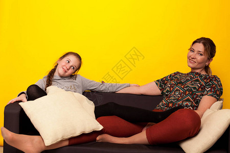 美丽的女孩和妈坐在黑沙发上身着自制图片
