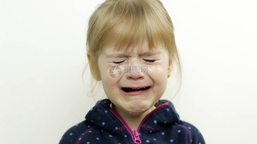 蹒跚学步的小女孩哭着流泪的画像在白色背景上隔离童年的概念儿童情绪的工作室拍摄特写金发小孩图片