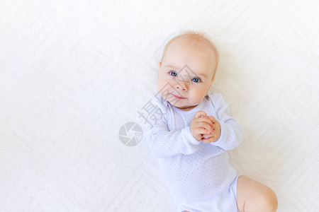 6个月大时穿白色泳装的小女婴肖像躺在她背上一张白图片