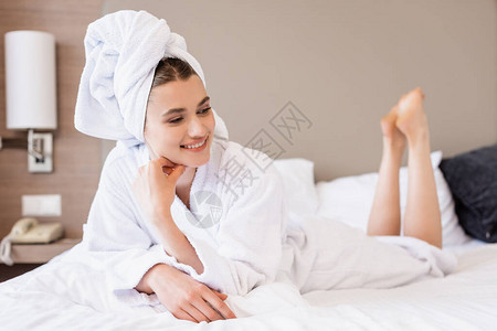 穿着毛巾和白浴袍的赤脚和喜悦妇女躺在旅图片