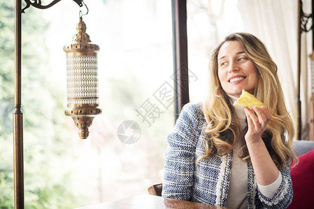 在蓝套房快乐的年轻迷人女孩独自在餐厅吃一块披萨在商业午餐图片