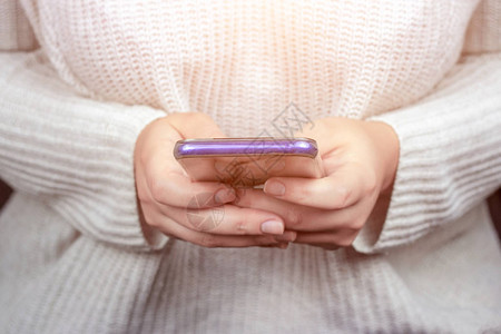 一个年轻女子手里拿着蓝色的移动智能手机看视频或浏览互图片