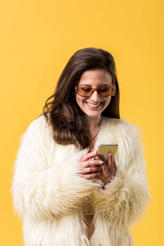 穿着毛皮外套和墨镜的快乐派对女孩使用在黄色上隔图片
