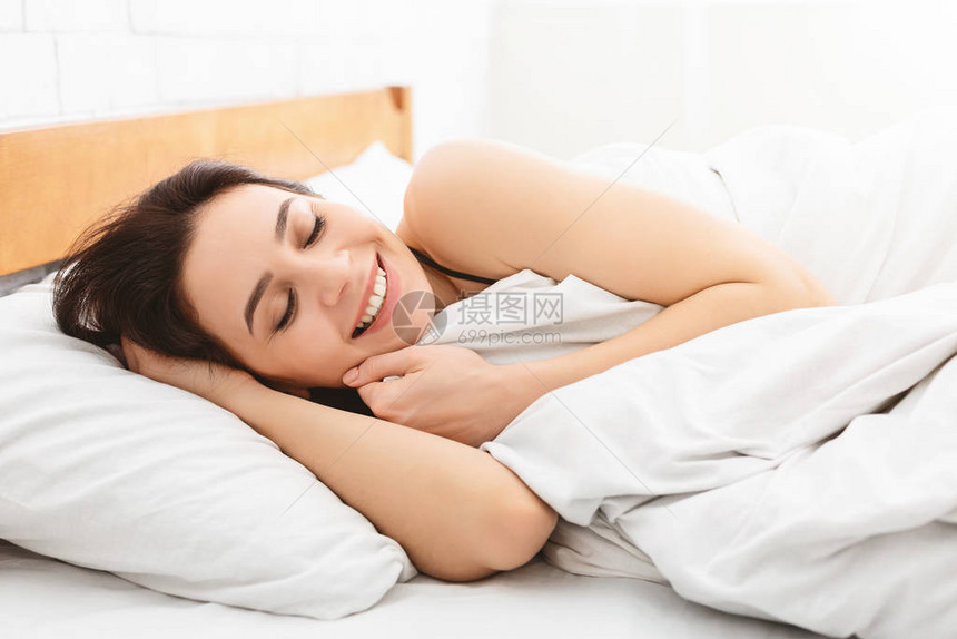 早上好睡得很安稳的女人躺在床图片