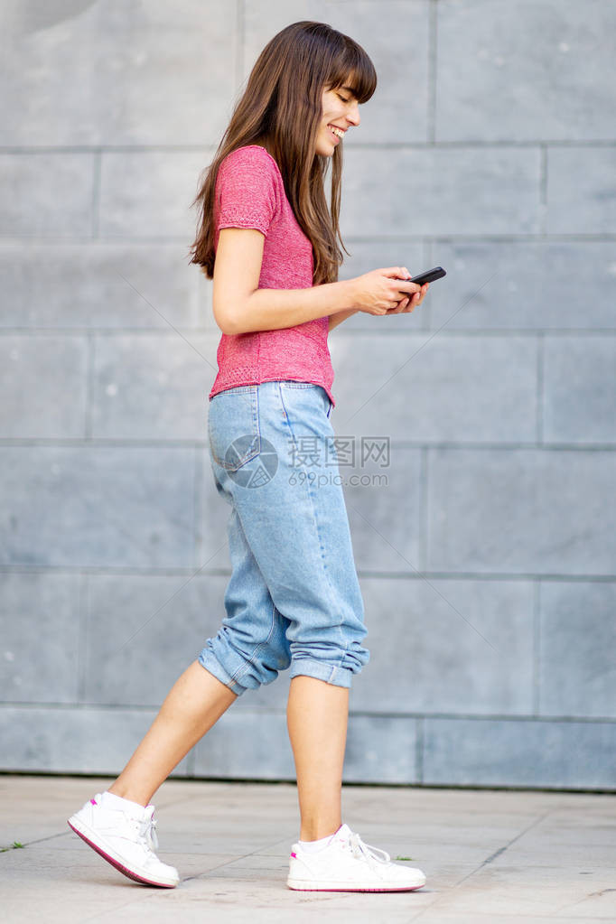 青年妇女用手机行走的完图片