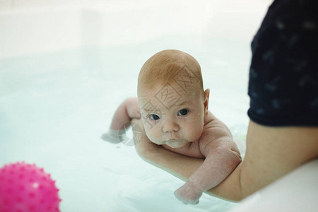 母亲的手在水中给两个月大的婴儿洗澡图片