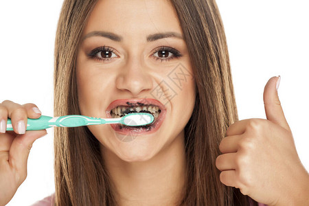 年轻女青年用黑色活木炭牙膏刷牙图片