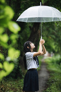 下雨时在自然行走道上带着雨伞走路的亚图片