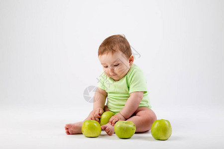 绿色健身服中的小可爱玩家坐在绿苹果中玩耍白色背图片