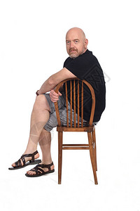 身穿凉鞋T恤和短裤的秃头男子坐在白色背景上图片