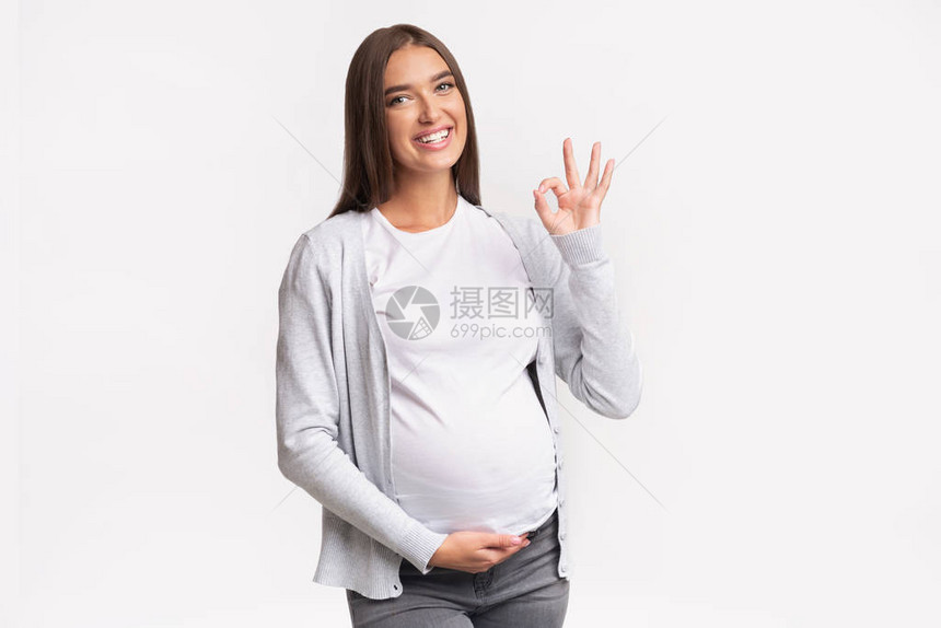 快乐的孕妇在白背景上站立图片