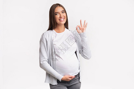快乐的孕妇在白背景上站立图片
