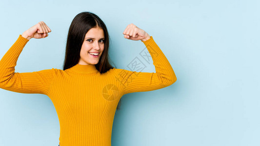 蓝色背景中孤立的年轻白人女用手臂展示力量姿态图片