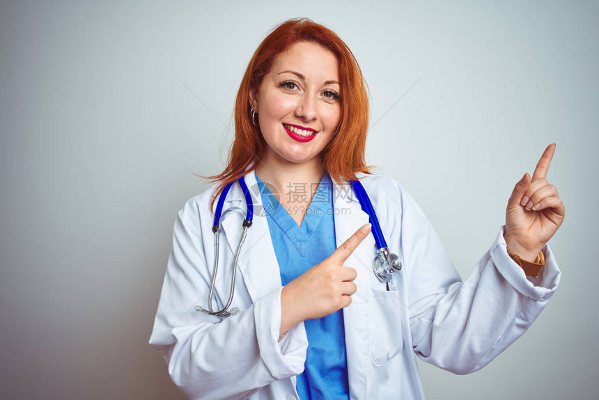 年轻红发女医生在白色孤立的背景上使用听诊器图片