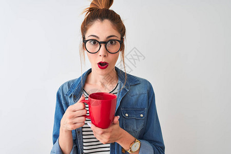 年轻美丽的红发女人在孤立的白色背景上喝着咖啡图片