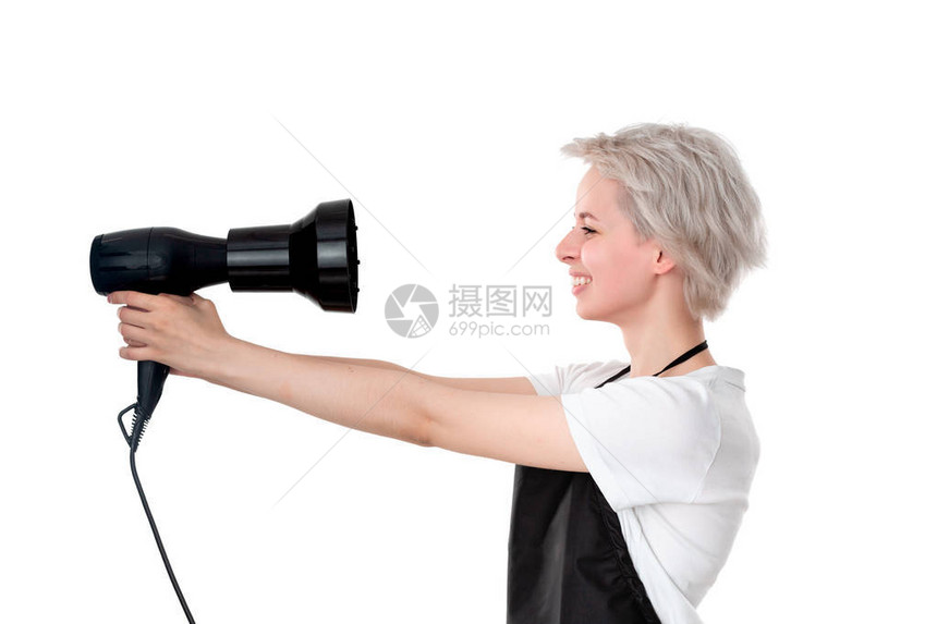 穿着白色T恤和黑色围裙的年轻漂亮美发师拿着专业的黑色吹风机图片