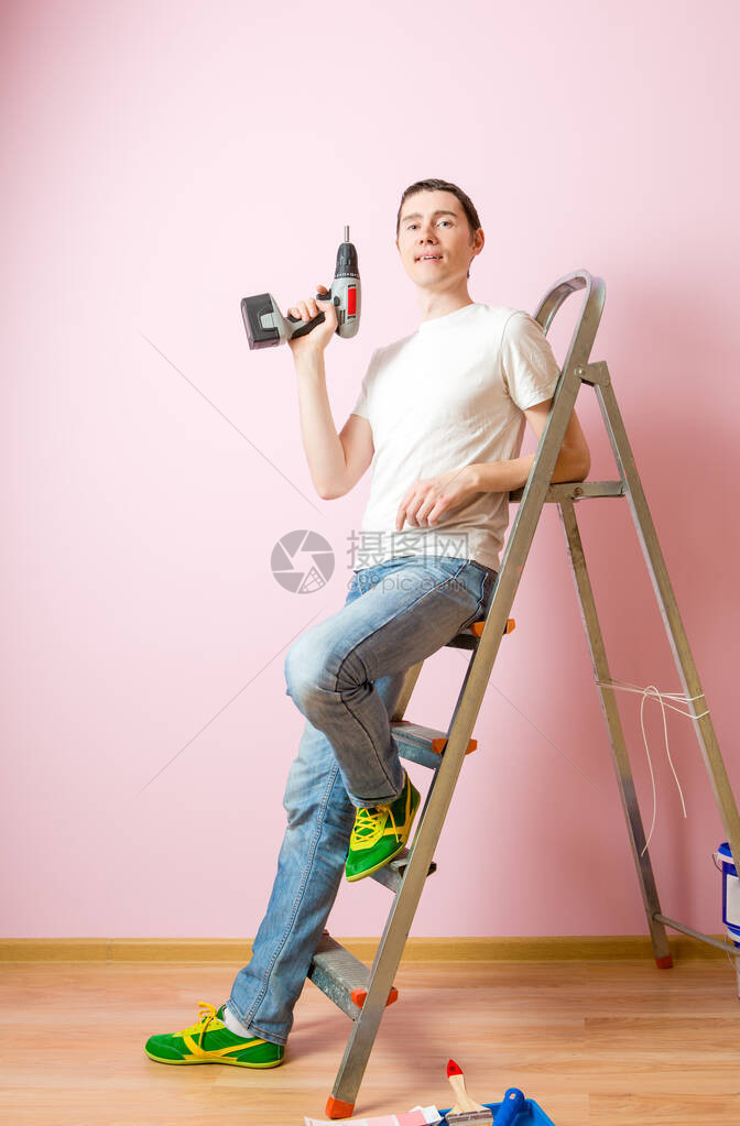 粉色墙背景的在梯子附近钻图片