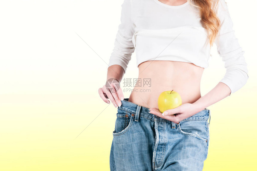 穿牛仔裤减肥瘦身苹果的年轻女人图片