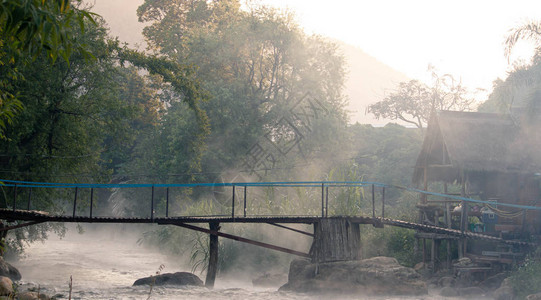 清晨蒸发和河上竹桥涌现淡水流的美丽景象缓慢地穿过天然岩石海滩漂流图片